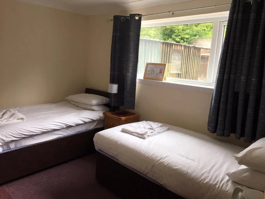 two beds in a room with a window at The Station Hotel in Alness