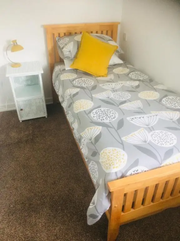 a bed in a room with a yellow pillow on it at Crossgates, Rosehearty in Rosehearty