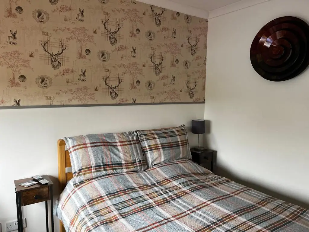 a bedroom with a bed with a plaid blanket at Exclusive Private double room, en-suite wet room Private entrance in Forres