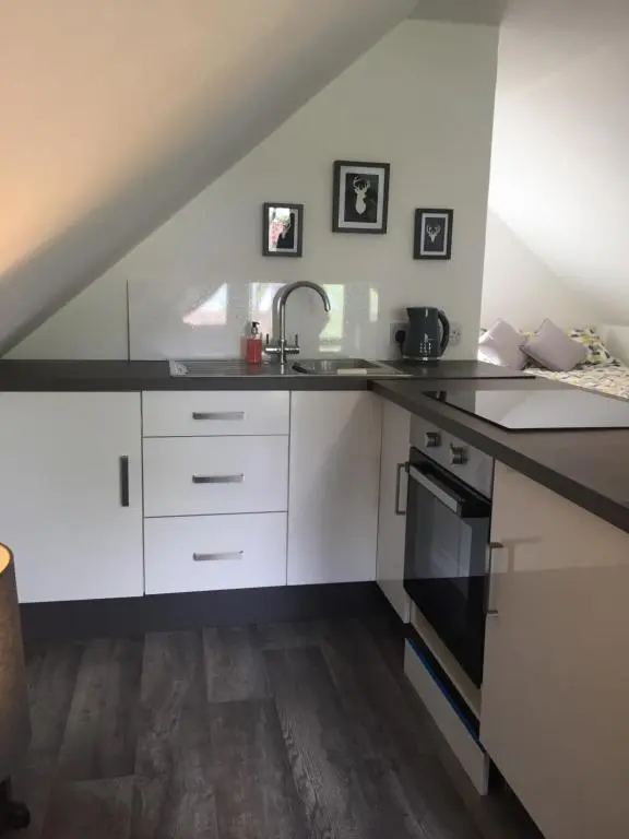 a kitchen with white cabinets and a sink at The Tree House in Inverness