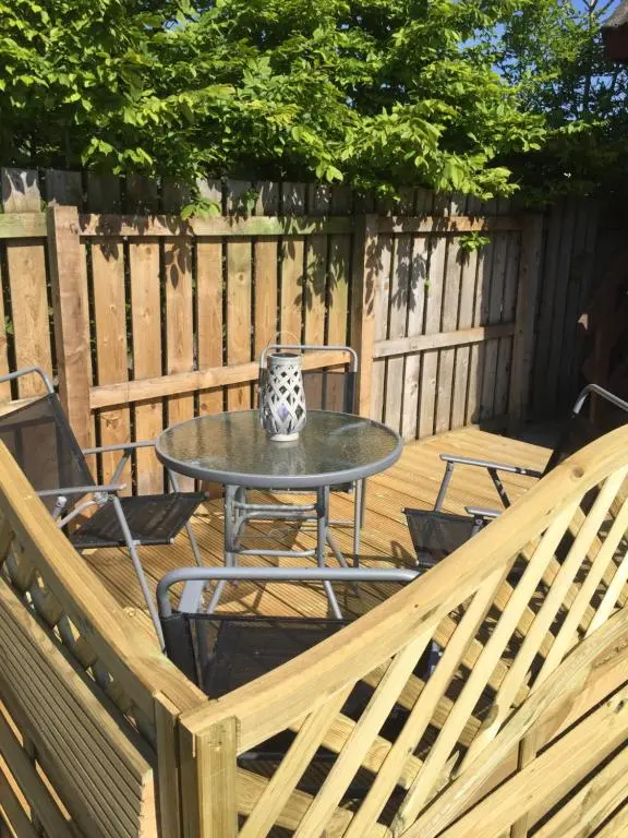 a patio with a table and chairs on a wooden deck at The Tree House in Inverness