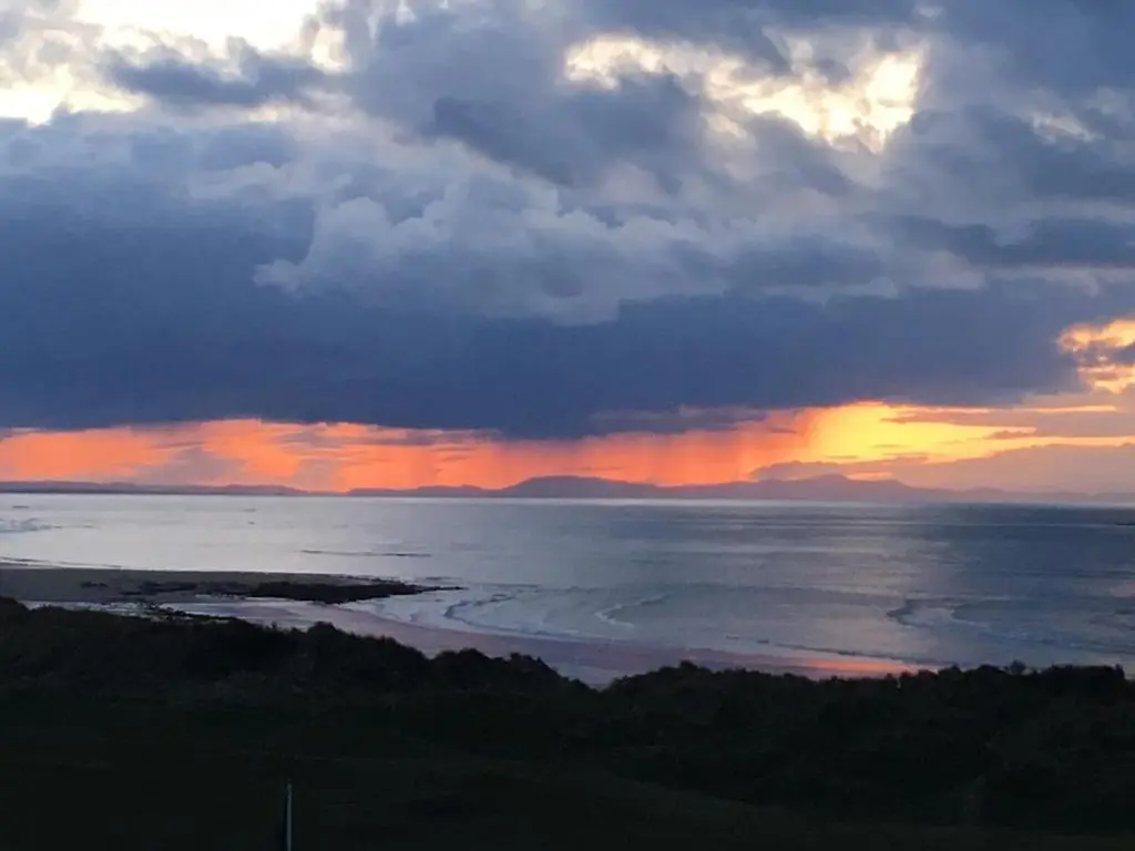 a sunset over a body of water with clouds at Cliffside in Lossiemouth