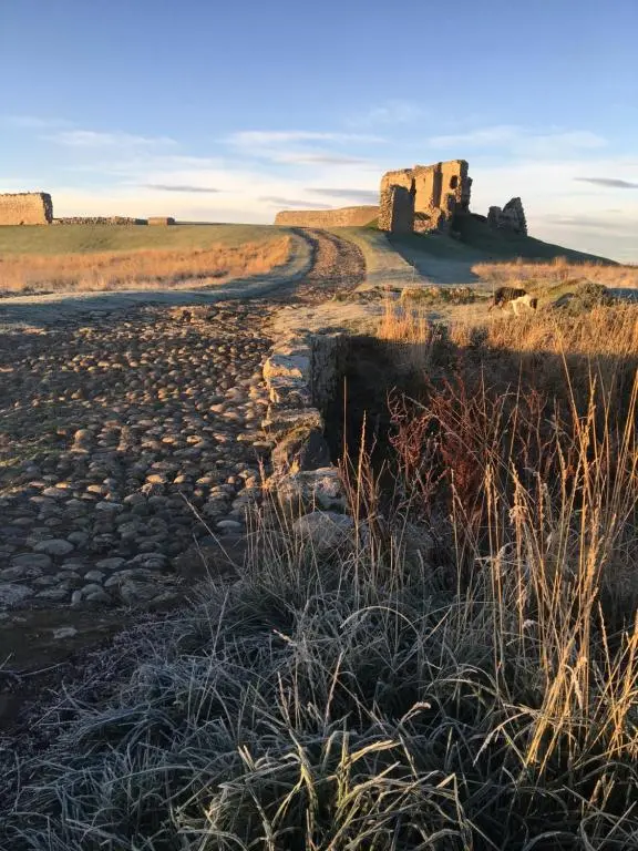a dirt road in a field with a castle in the distance at Cliffside in Lossiemouth