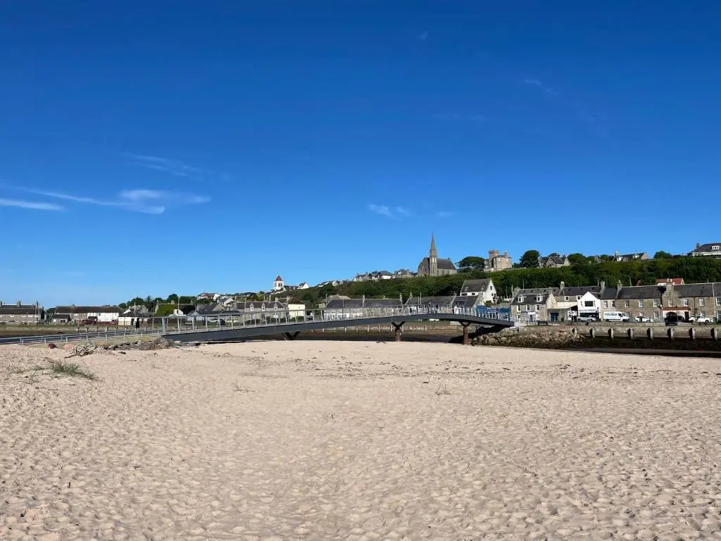 a sandy beach with a bridge in the background at Cliffside in Lossiemouth