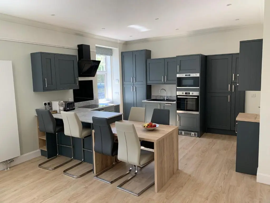 a kitchen with blue cabinets and a table and chairs at Cliffside in Lossiemouth