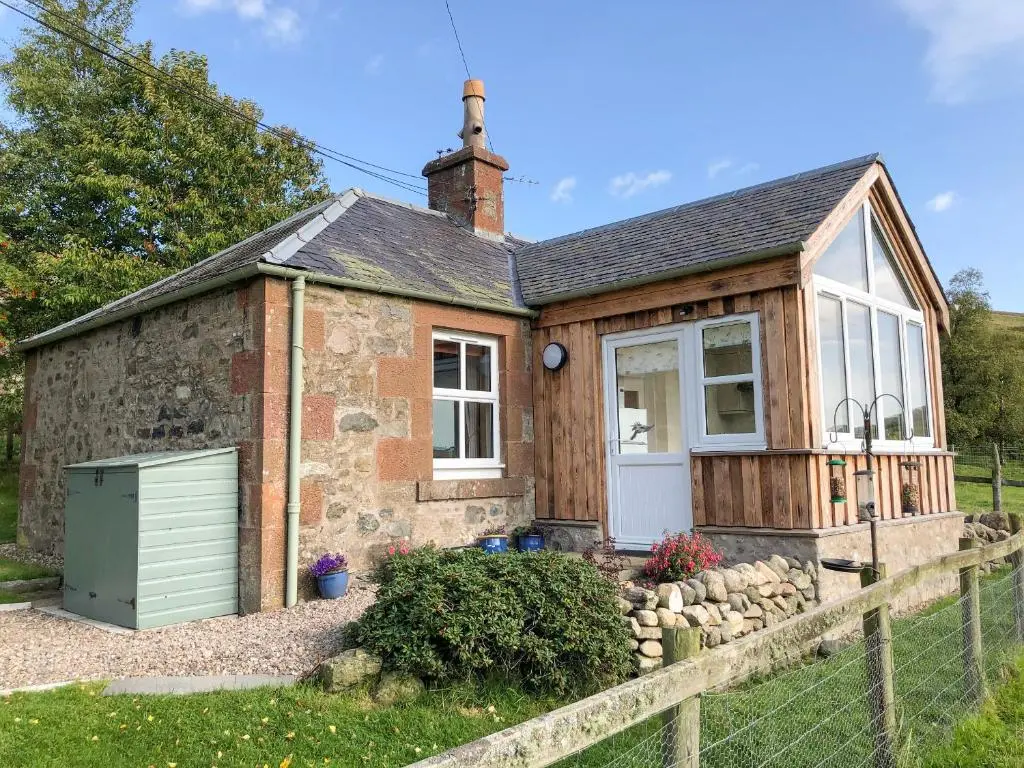 a small stone cottage with a white door at The Bothy in Kirriemuir
