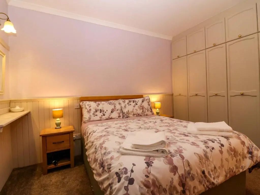 a small bedroom with a bed and two lamps at The Bothy in Kirriemuir