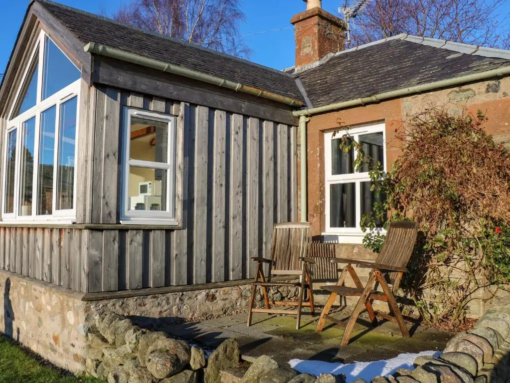 a house with two chairs outside of it at The Bothy in Kirriemuir