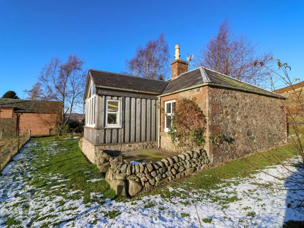 an old stone house with a stone wall at The Bothy in Kirriemuir