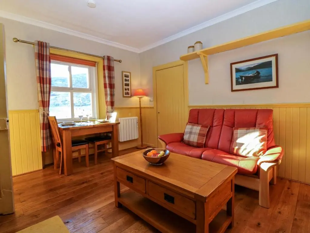 a living room with a red couch and a table at The Bothy in Kirriemuir