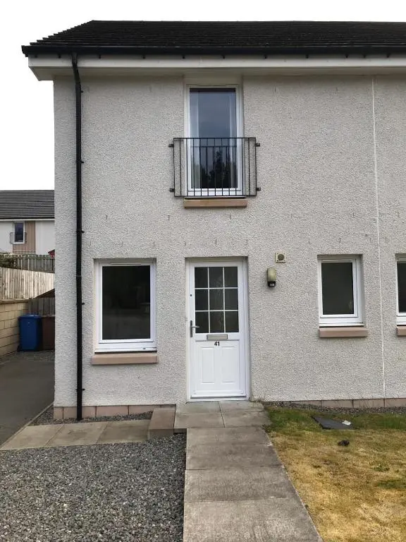 a white house with a white door and a balcony at 41 Larchwood Drive Holiday Home in Inverness