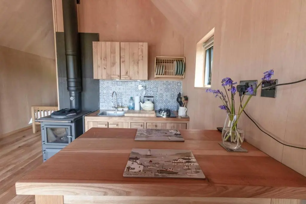 a kitchen with a wooden table and a stove at Birdwatcher's Cabin in Golspie