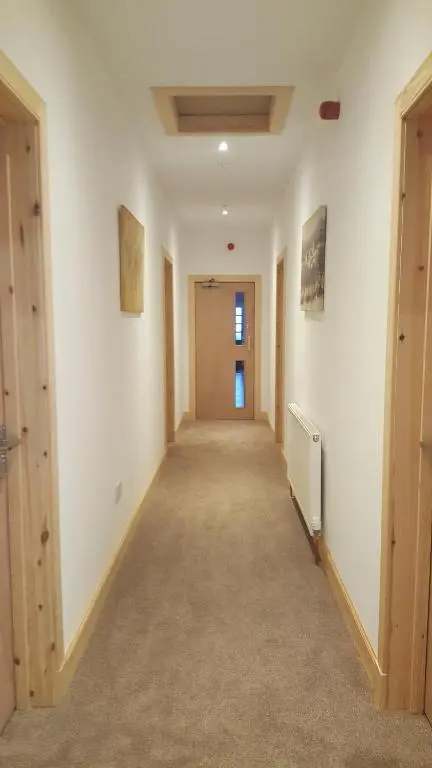 a hallway of an empty room with a door and a hallwayngthngthngthngth at Helmsdale Lodge Hostel - all rooms en-suite in Helmsdale