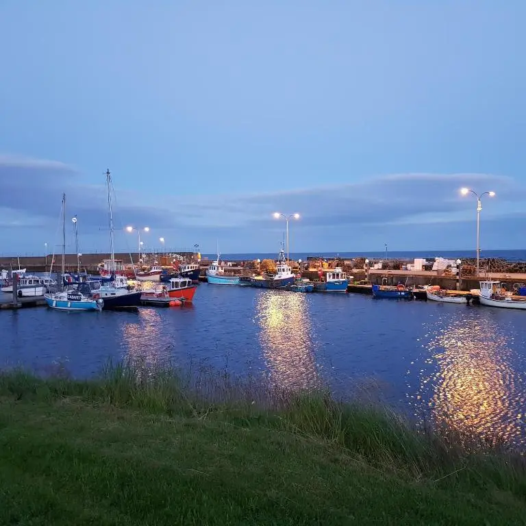 a marina with boats in the water at dusk at Helmsdale Lodge Hostel - all rooms en-suite in Helmsdale