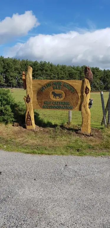 a sign for a bear park with two wooden trees at Delny Muir House in Invergordon