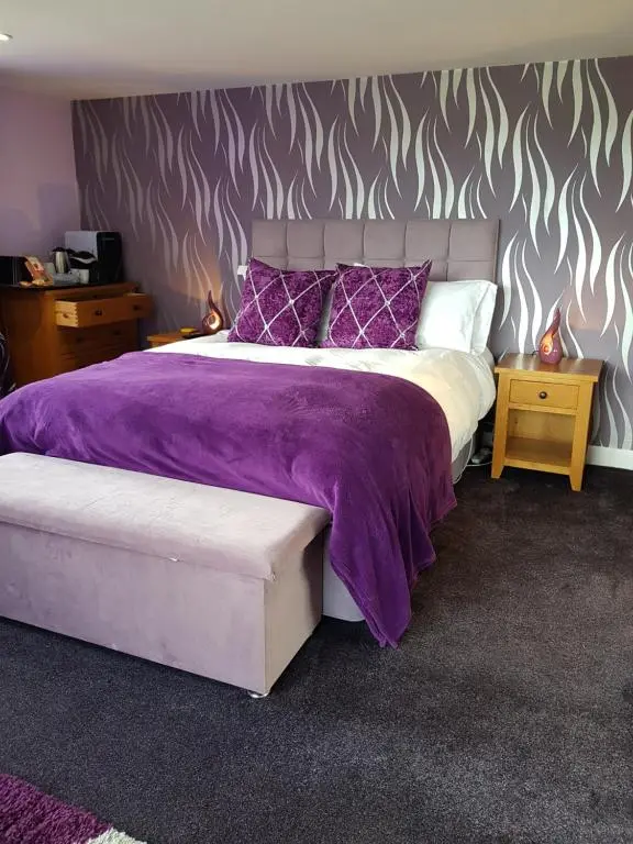 a bedroom with a large bed with purple blankets and pillows at Delny Muir House in Invergordon