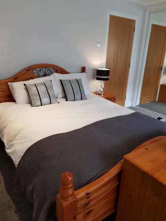 a bedroom with a large wooden bed with pillows at Delny Muir House in Invergordon
