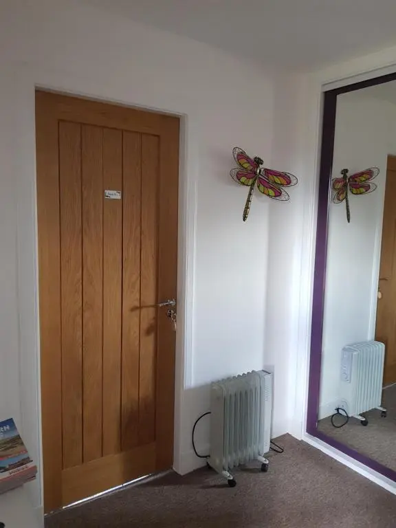 a room with a wooden door and a mirror at Delny Muir House in Invergordon