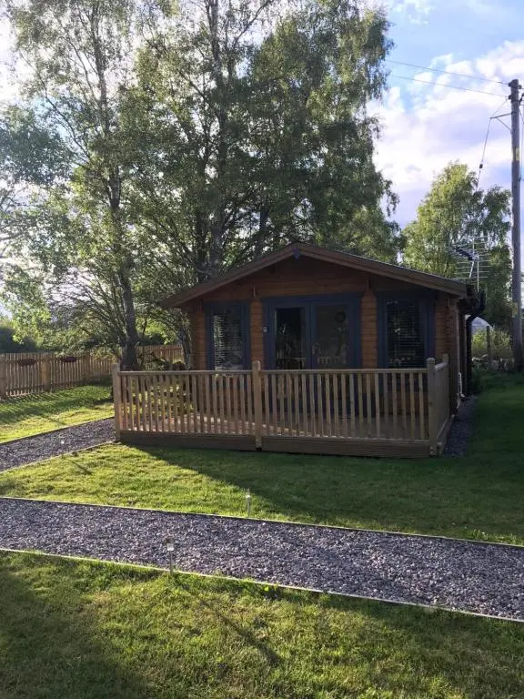 a log cabin in a yard with a fence at Star Cabin Lairg in Lairg