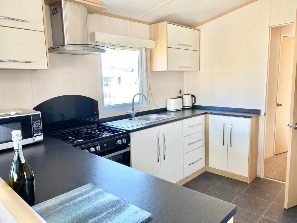 a kitchen with white cabinets and a black counter top at 87 Lighthouse View Lodge in Lossiemouth