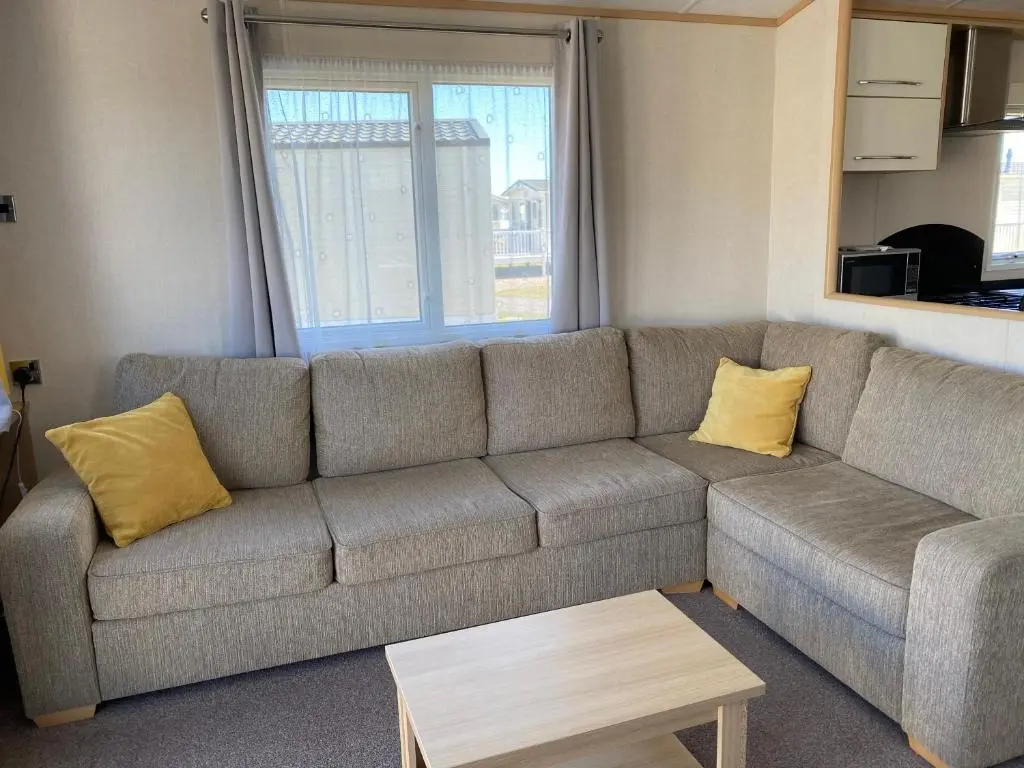 a living room with a gray couch with yellow pillows at 87 Lighthouse View Lodge in Lossiemouth