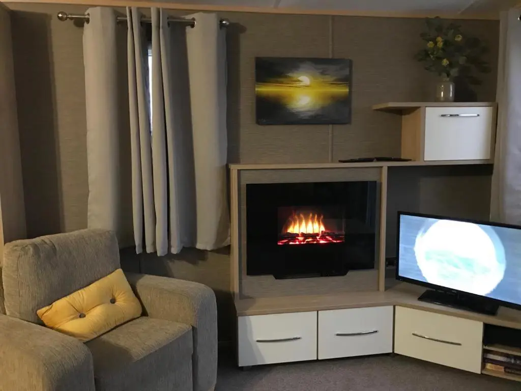 a living room with a fireplace and a television at 87 Lighthouse View Lodge in Lossiemouth