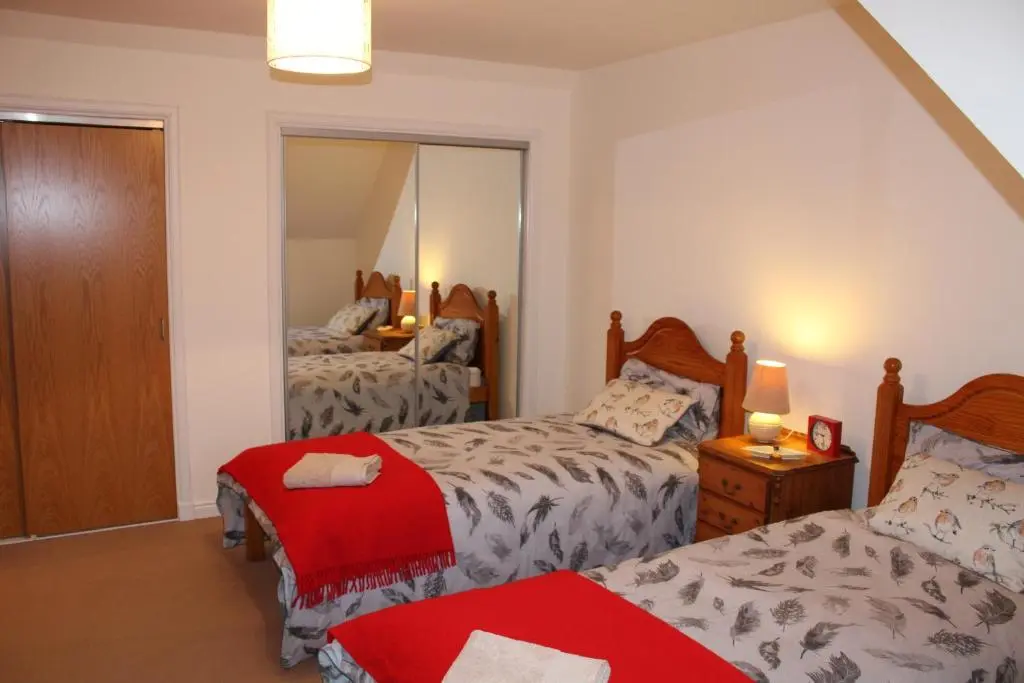 a bedroom with two beds and a mirror at Roualeyn in Huntly