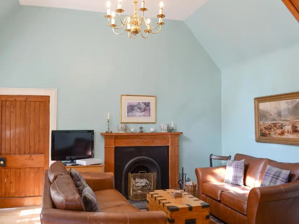 a living room with leather furniture and a fireplace at Tressady Coach House in West Langwell