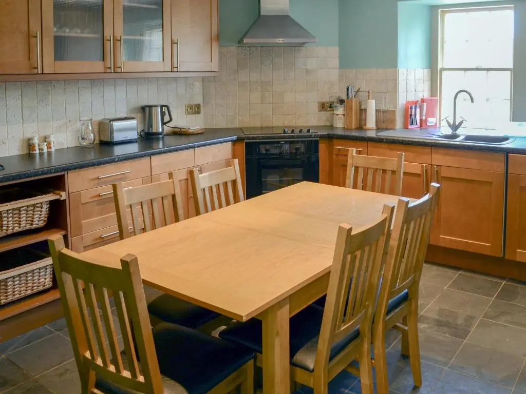 a kitchen with a wooden table and chairs at Tressady Coach House in West Langwell