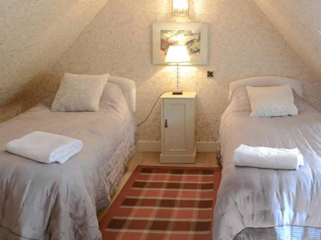 a attic bedroom with two beds and a lamp at Tressady Coach House in West Langwell