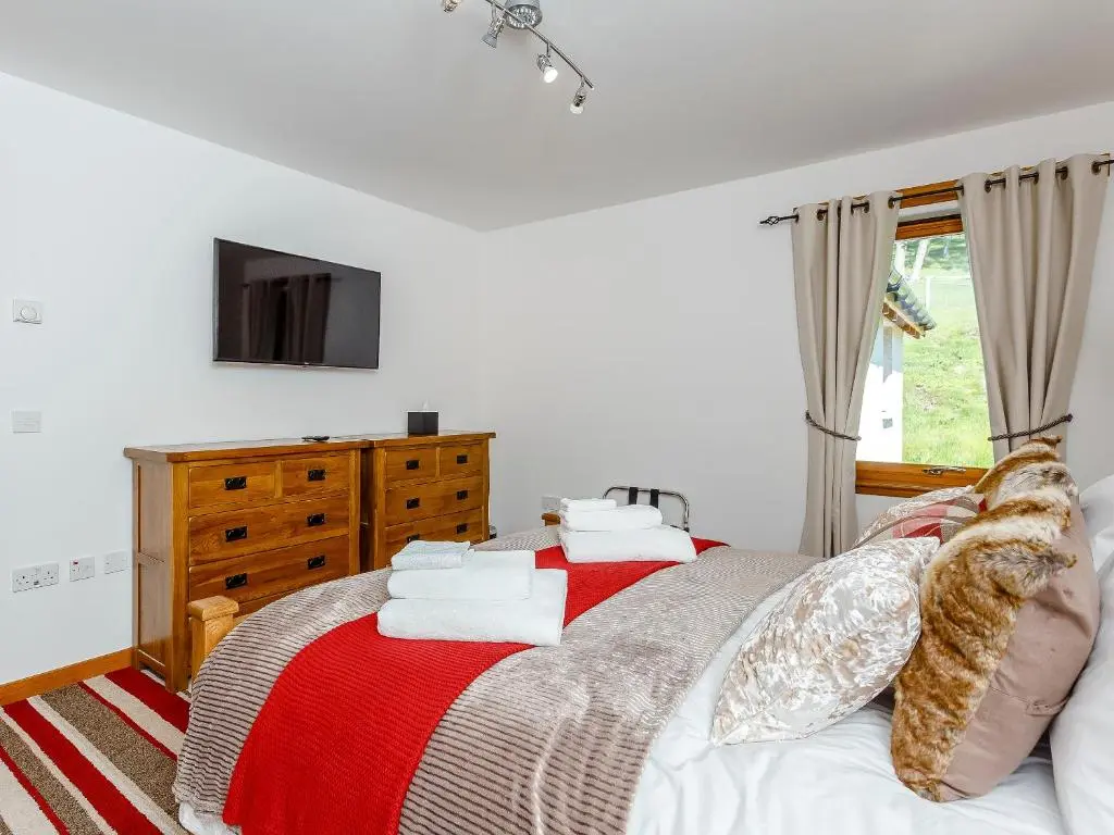 a bedroom with a bed with a red and white blanket at Sunnyside House in Duthil