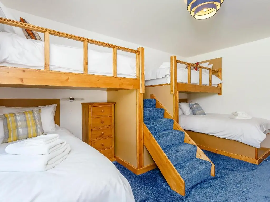 a bedroom with two bunk beds and a staircase at Sunnyside House in Duthil