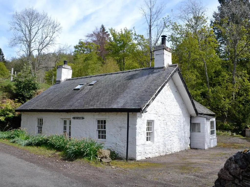 a small white building with a black roof at Burnmouth in Balnaboth