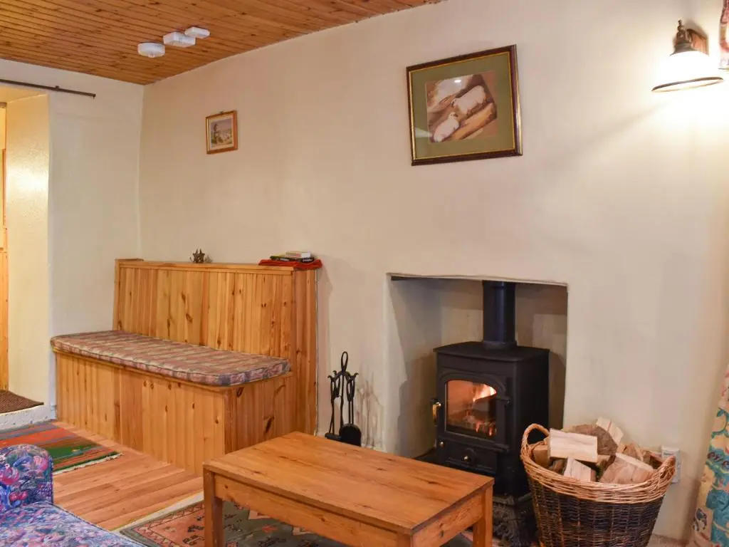 a living room with a fireplace and a wood stove at Burnmouth in Balnaboth