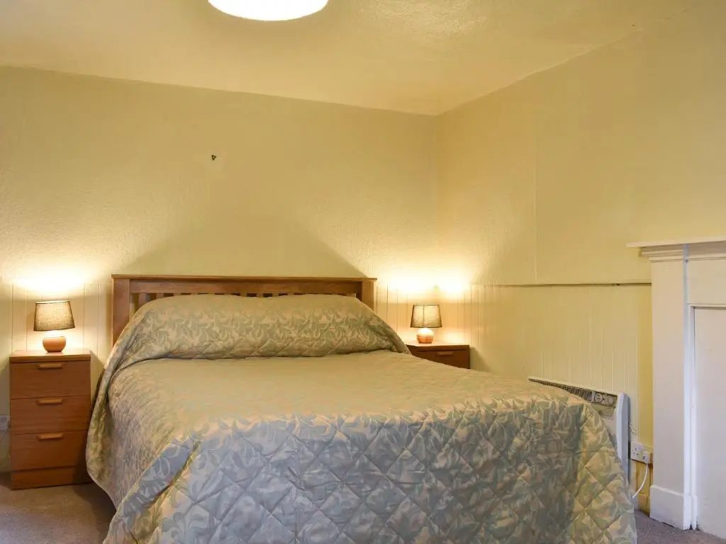 a bedroom with a bed with two night stands and two lamps at Burnmouth in Balnaboth