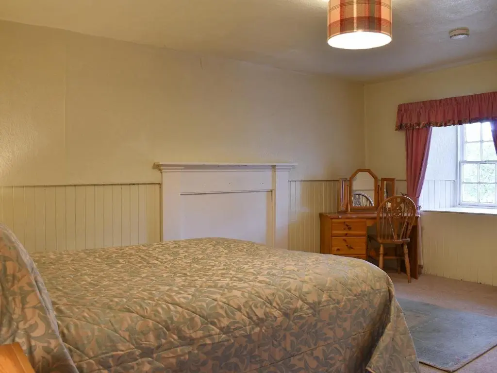 a bedroom with a bed and a desk and a window at Burnmouth in Balnaboth