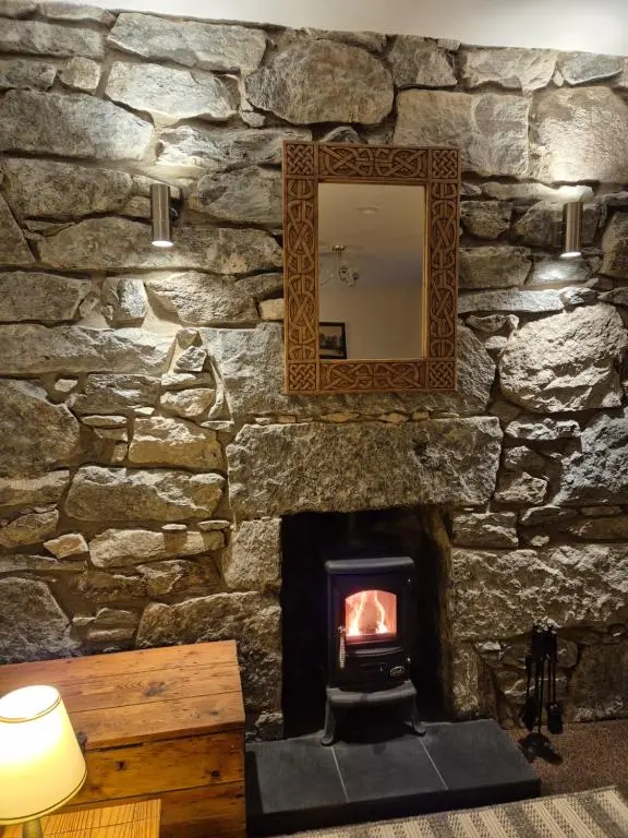 a stone wall with a fireplace and a mirror at The Old Convent Holiday Apartments in Fort Augustus