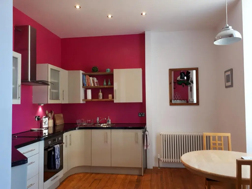 a kitchen with pink walls and a table in it at The Old Convent Holiday Apartments in Fort Augustus