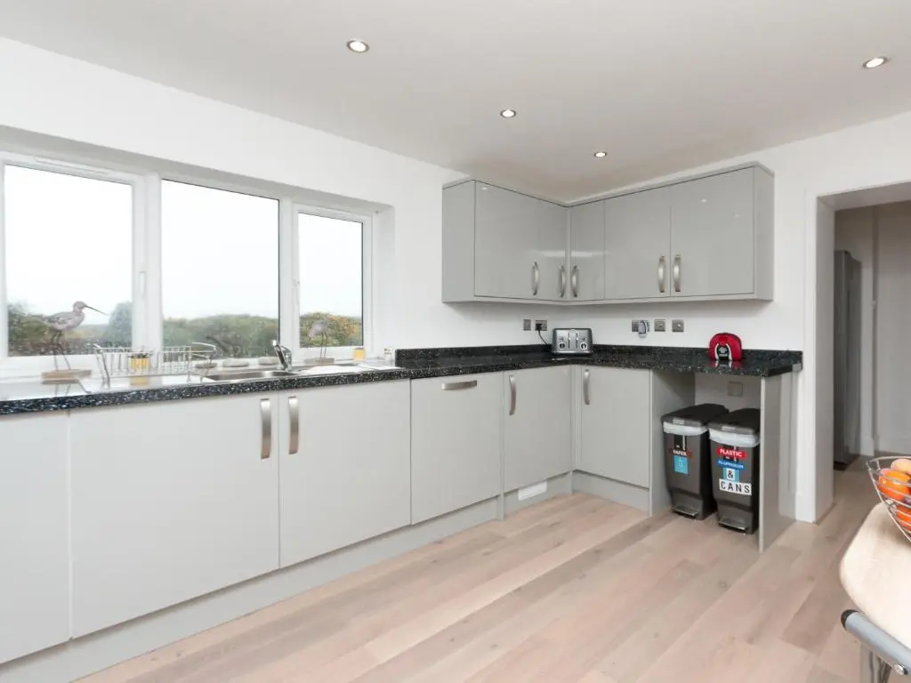 a white kitchen with white cabinets and windows at Inverspey in Kingston