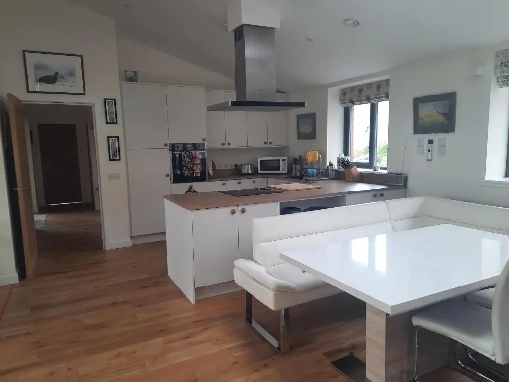 a kitchen with a white table and a white couch at Carnmore Cottage in Inverness