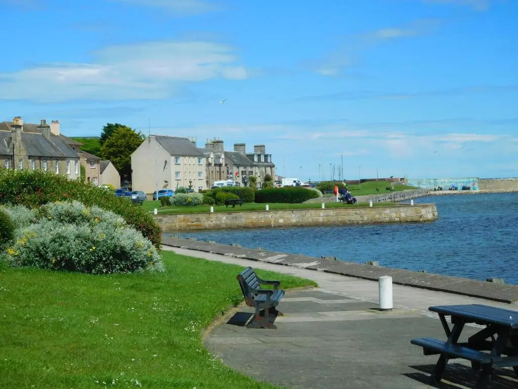 a park bench sitting next to a body of water at WELCOMEHOUSE close to east beach, shops, restaurants and RAF base in Lossiemouth