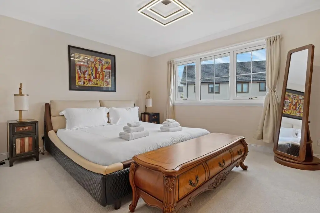 a bedroom with a bed with a table and a mirror at Taigh d'Luxe in Inverness