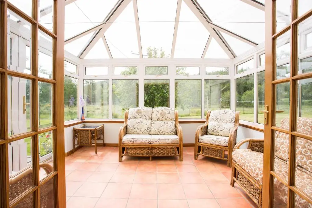 a conservatory with two chairs and windows at Juniper Hill Loch Achilty in Contin