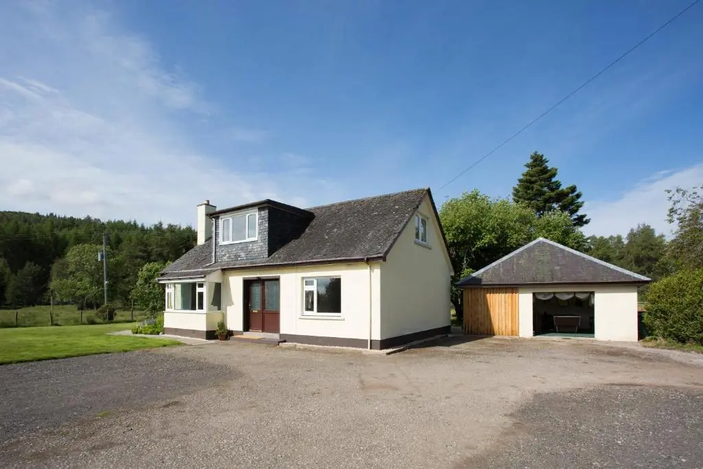 a white house with a garage in a driveway at Juniper Hill Loch Achilty in Contin