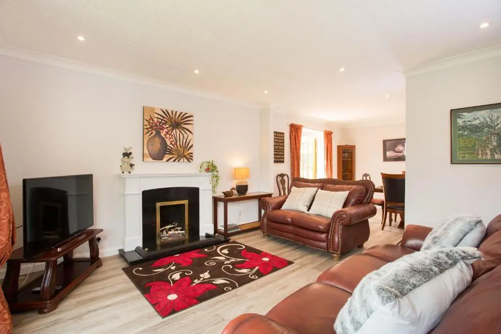 a living room with a couch and a fireplace at Juniper Hill Loch Achilty in Contin