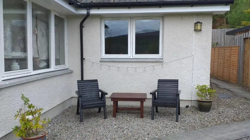 three chairs and a table in front of a house at The Studio in Drumnadrochit
