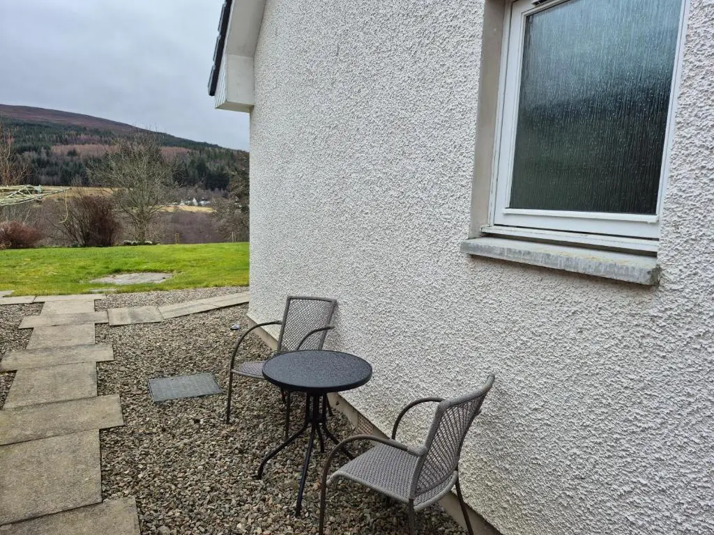 a patio with two chairs and a table and a window at The Studio in Drumnadrochit