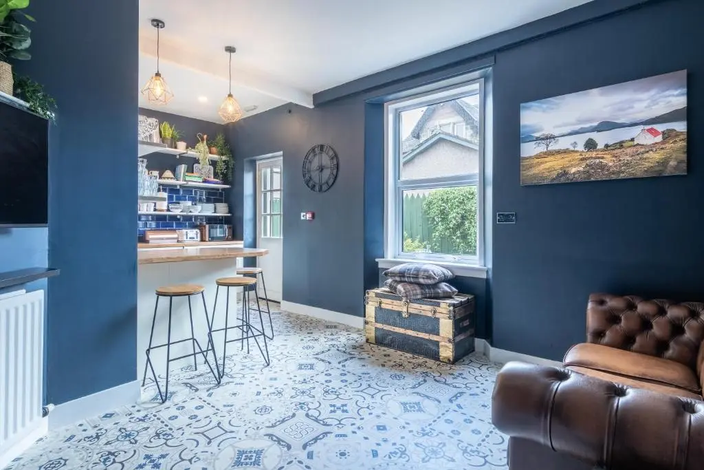 a living room with blue walls and a bar with stools at West of the Ness in Inverness