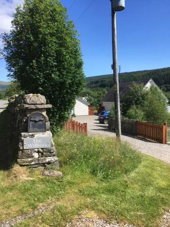 a stone sign in the grass next to a street at The Willows in Dalchreichart