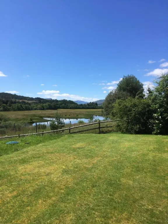 a field with a fence and a river in the background at The Willows in Dalchreichart